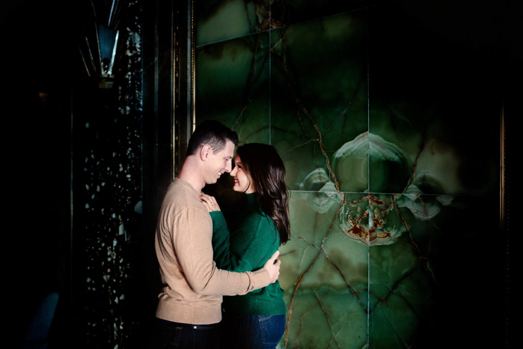 Couple looking in to each others eyes smiling in front of an emerald green wall. 8 engagement session prep tips.