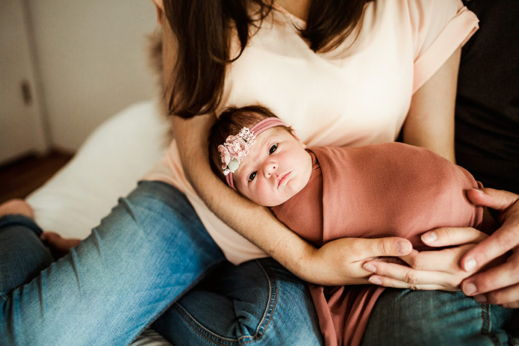 Couple holding their baby girl who is looking at the camera. Studio Newborn Session Guide