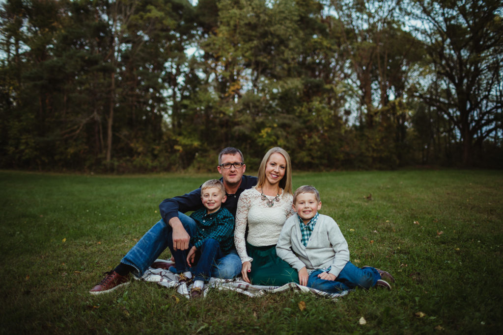 Family in the fall sitting in a park, on a blanket looking at the camera. 10 tips for choosing outfits for your family session