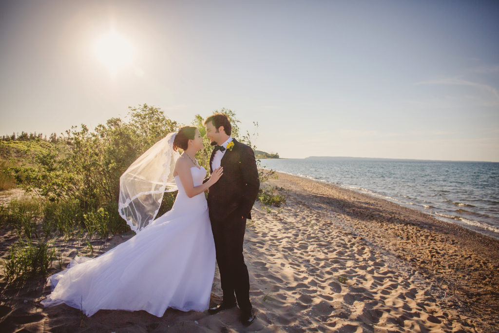 A bride & groom stand on the shores of Lake Michigan in Glen Arbor Michigan looking at each other. 8 reasons small weddings kick ass