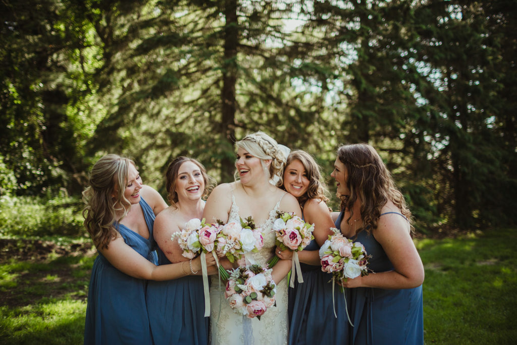 Bride with her wedding party looking at each other laughing. Essential to dos once you're engaged!