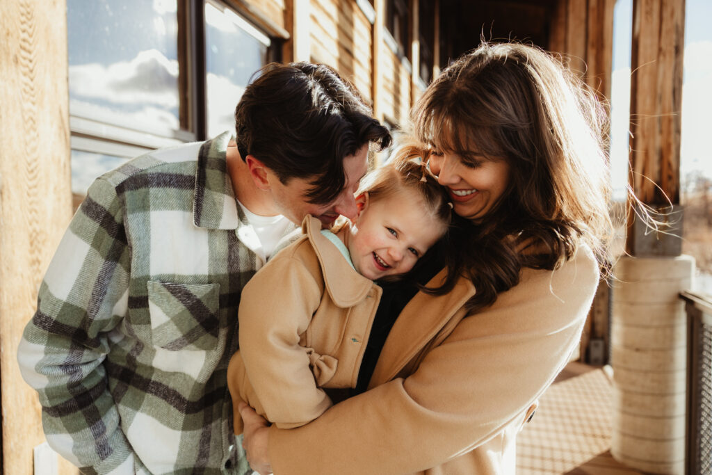 Parents hugging their young child during an outdoor winter family session in Michigan